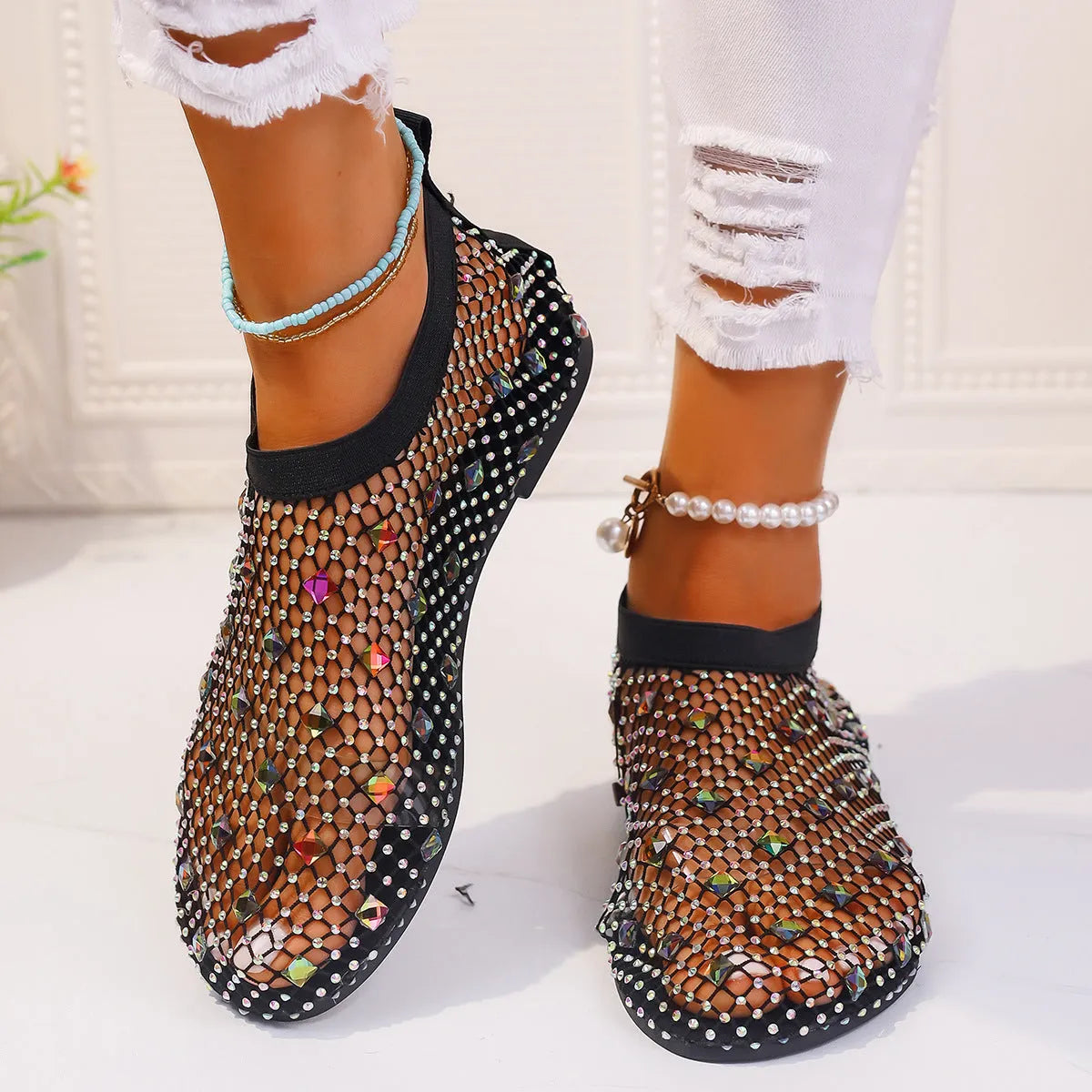 Women's flat sandals with colourful rhinestones on a mesh upper and rubber sole.