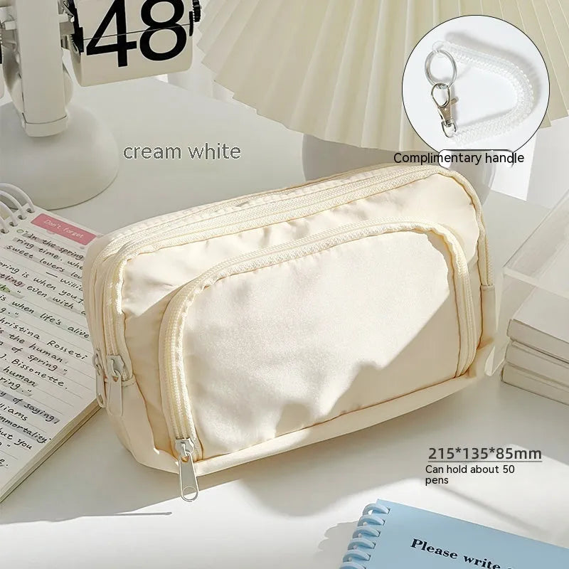 Double layer zippered pencil case in blue with a gift handle, shown next to pens and pencils.