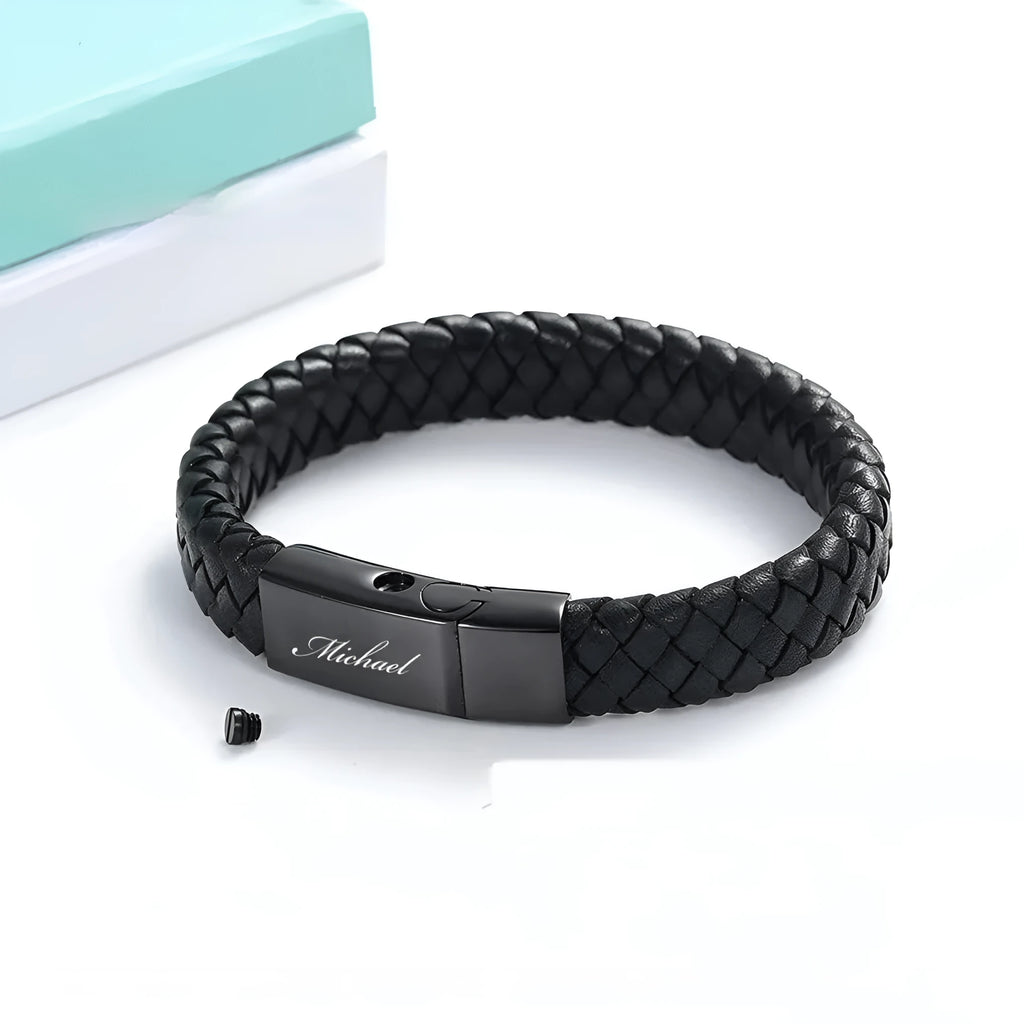 Black leather bracelet with a small stainless steel casket charm, shown in a gift box.