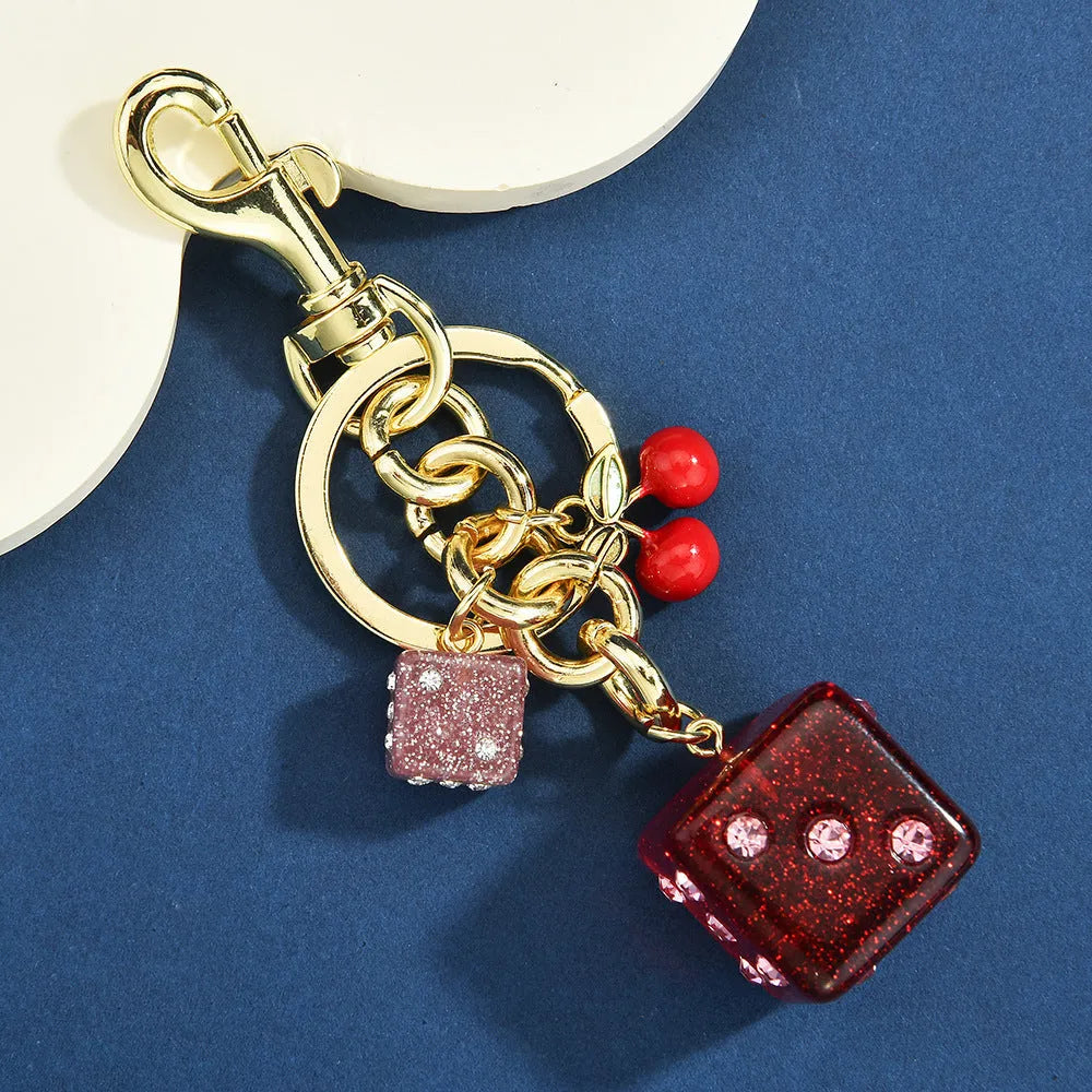 Square metal keychain pendant with a vintage cherry red and white dice design.