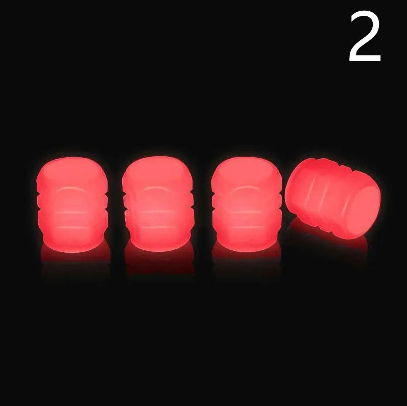 Set of luminous green rubber tyre valve caps on a car wheel valve stem, glowing in low light.