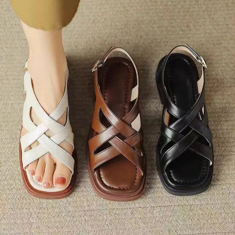 Women's black patent leather square toe beach sandals with cross-band strap on a low rubber sole.