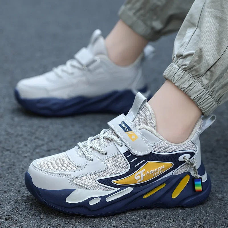 Boys' blue and black platform sports running shoes with Velcro straps on a hard ground surface.
