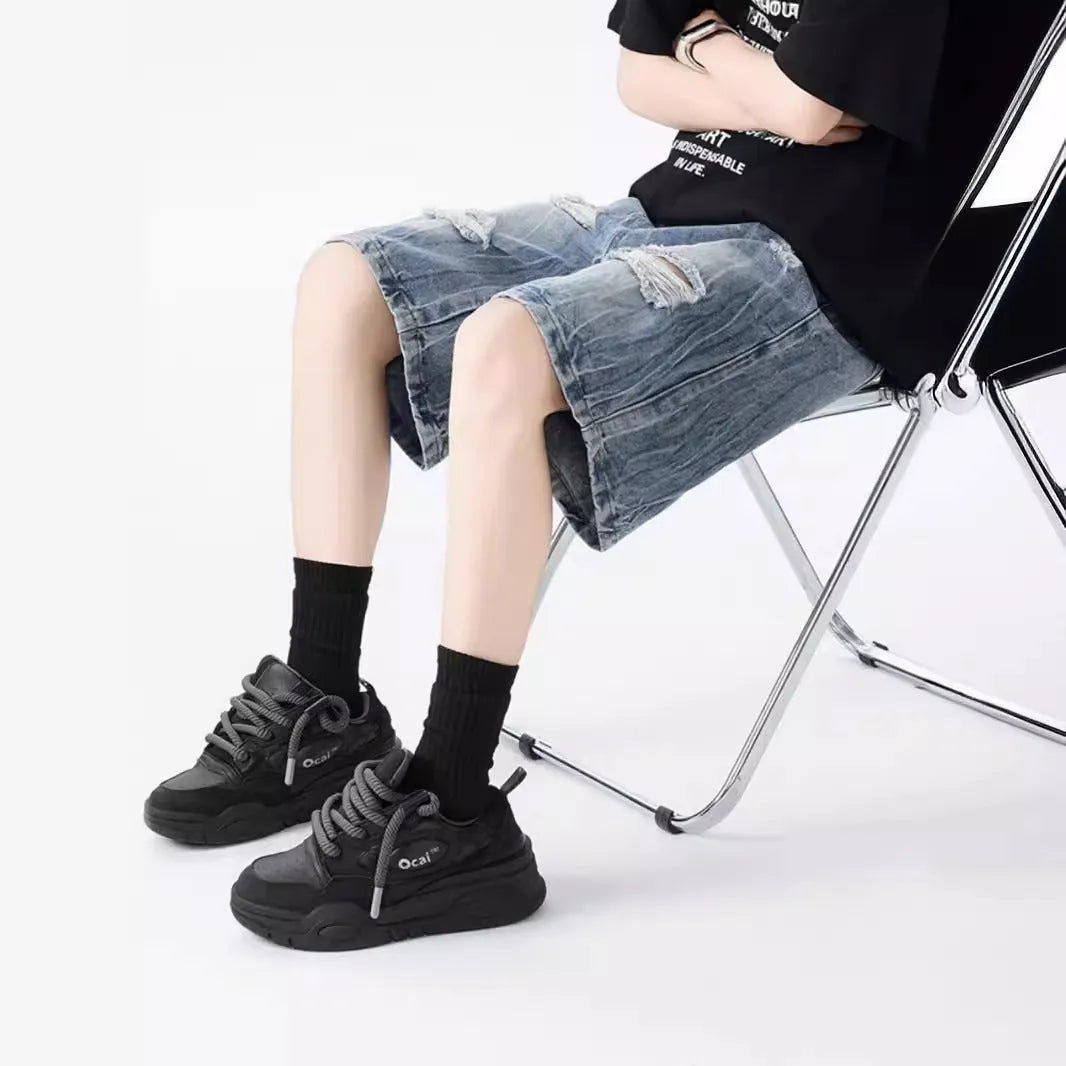 Man wearing black washed ripped denim shorts in a loose, retro style