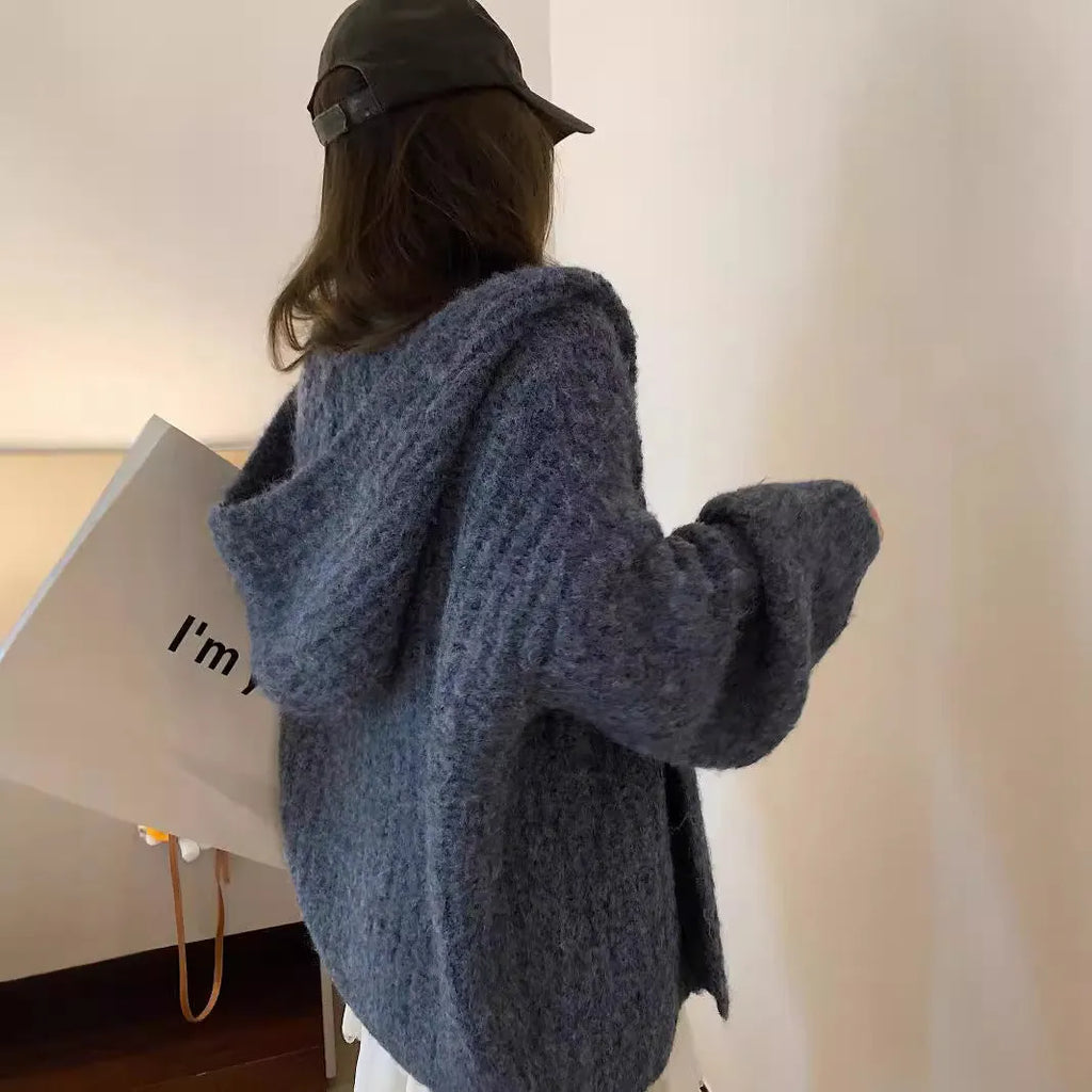 Women's retro-style thick knitted hooded cardigan in dark grey, shown open over a top.