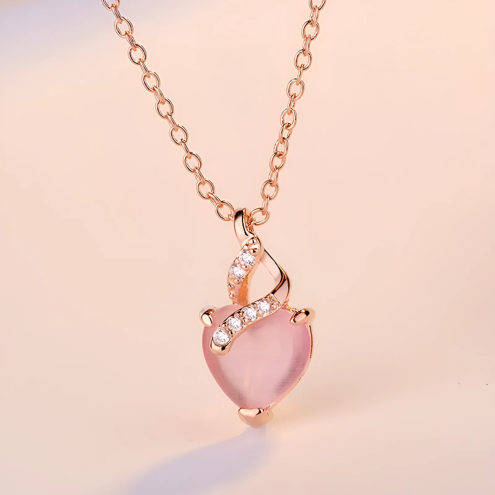 Women's rose gold necklace with a heart-shaped pink crystal pendant on a cross chain.