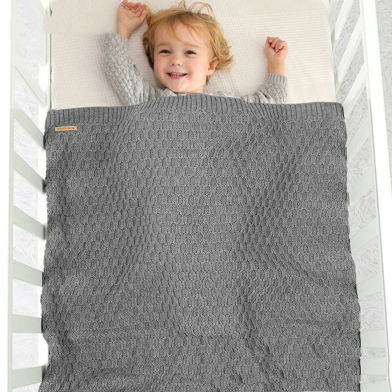 Infant hug blanket with three-dimensional lines pattern in a solid colour, measuring 70 by 90 centimetres.